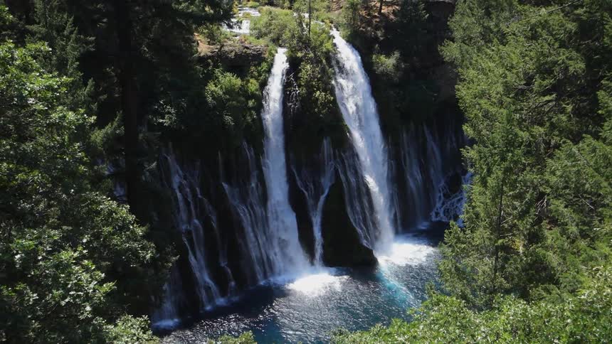 Two waterfalls are flowing into a deep blue lake