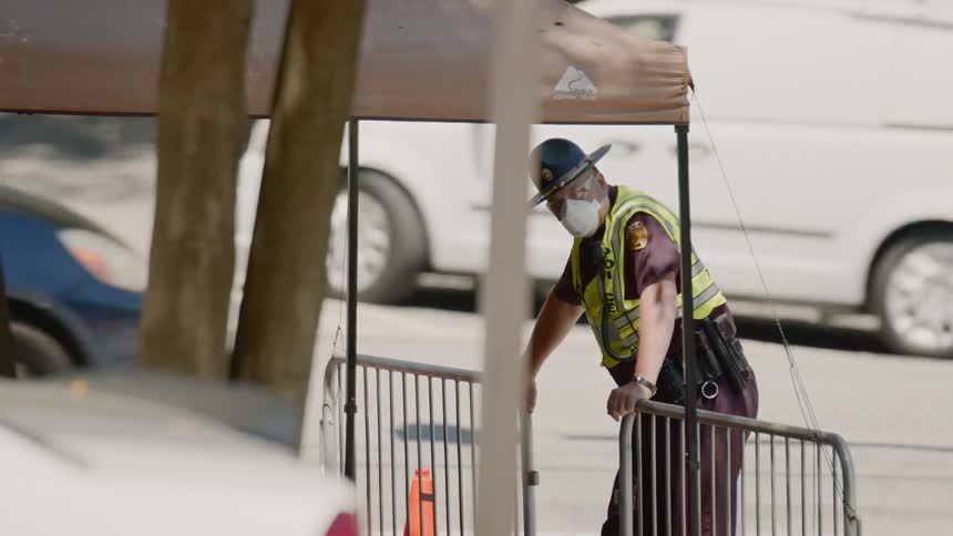 An officer in a mask stands next to a road