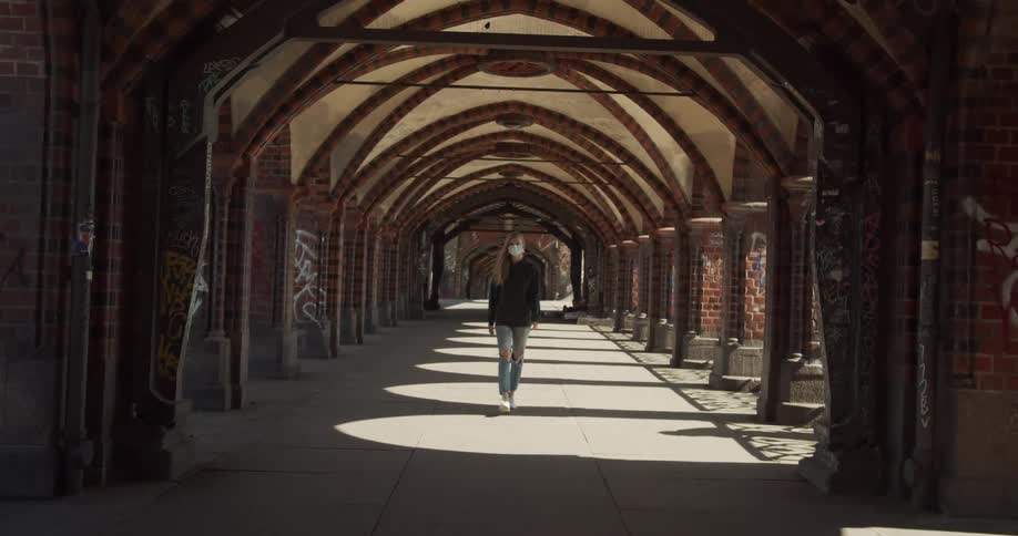Woman walks past graffiti covered pillars of covered walkway