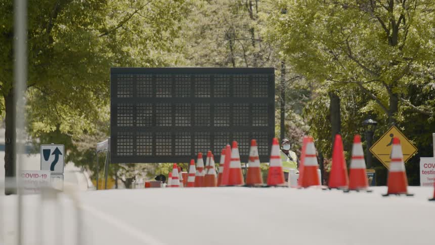 A worker watches the side of the road near a sign