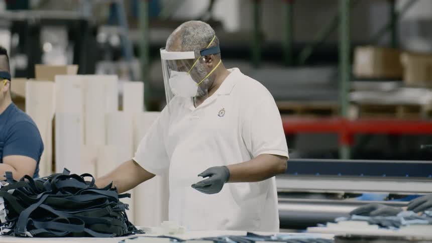 Workers in warehouse wearing face masks assemble products