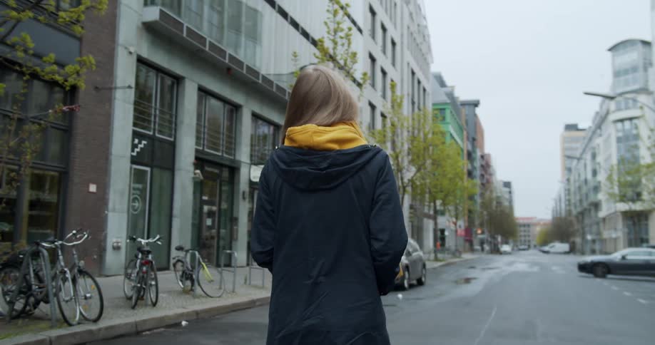 A woman walks down a city street with no traffic