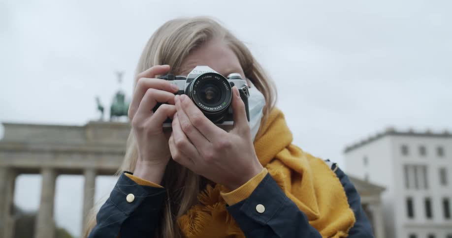 Woman wearing face mask takes photos in front of the brandenburg gate berlin