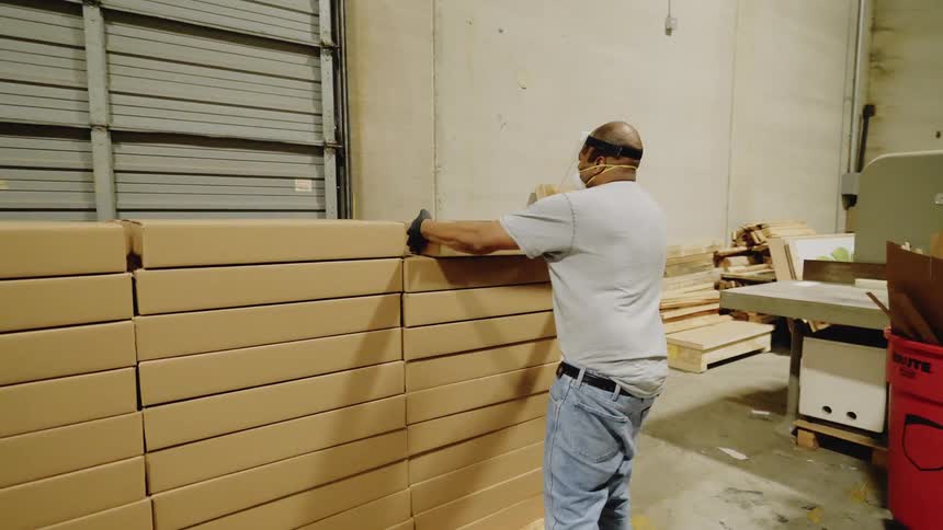 Worker wearing a face mask piles up boxes in the warehouse