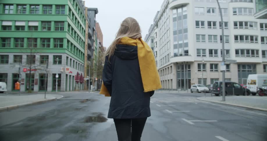 A woman with a yellow scarf walking down a city street