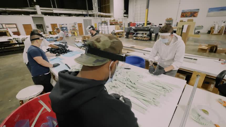 Workers wearing face mask assemble products in warehouse