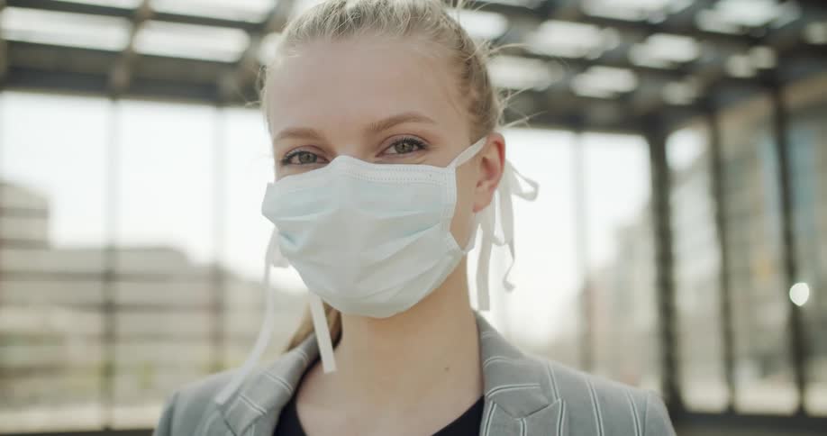 A teen wearing a mask stands outside
