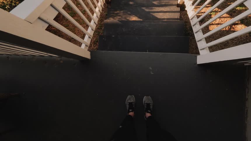 A person putting on a face mask while standing on the porch of a house before descending the steps