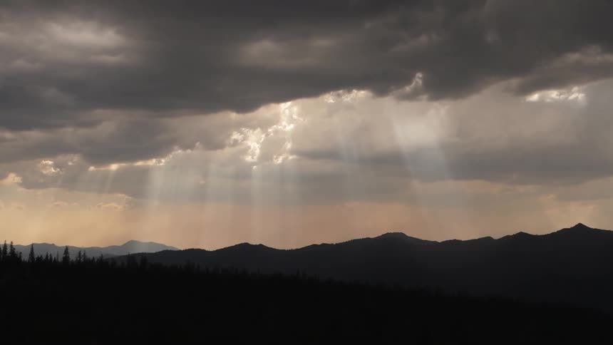 Sun shines through the clouds onto the hills and trees