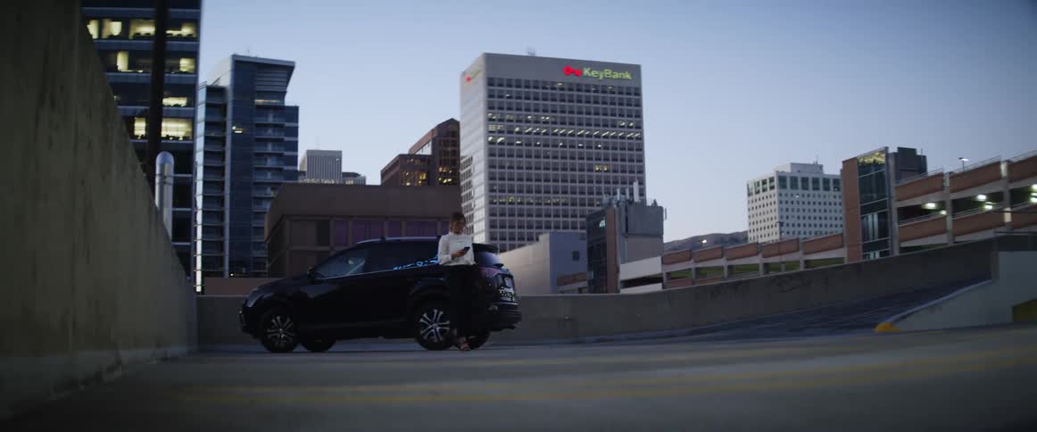 Woman leaving car parked in parking garage in city at sunset