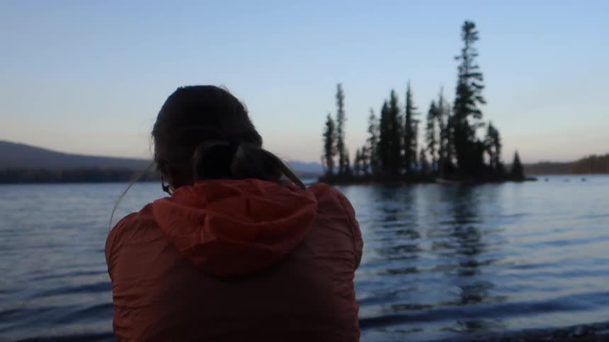 A woman sits at the edge of the water