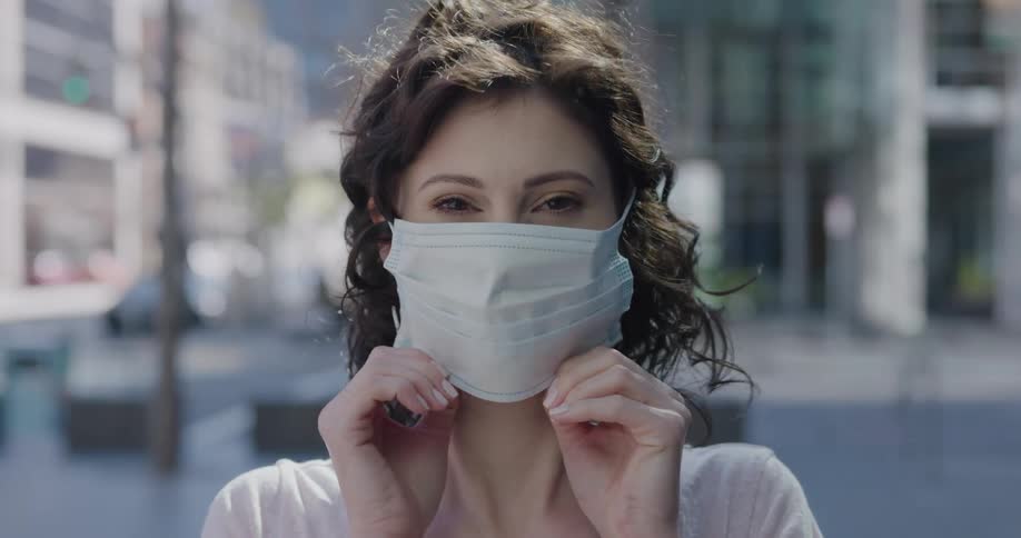 A woman putting on a face mask