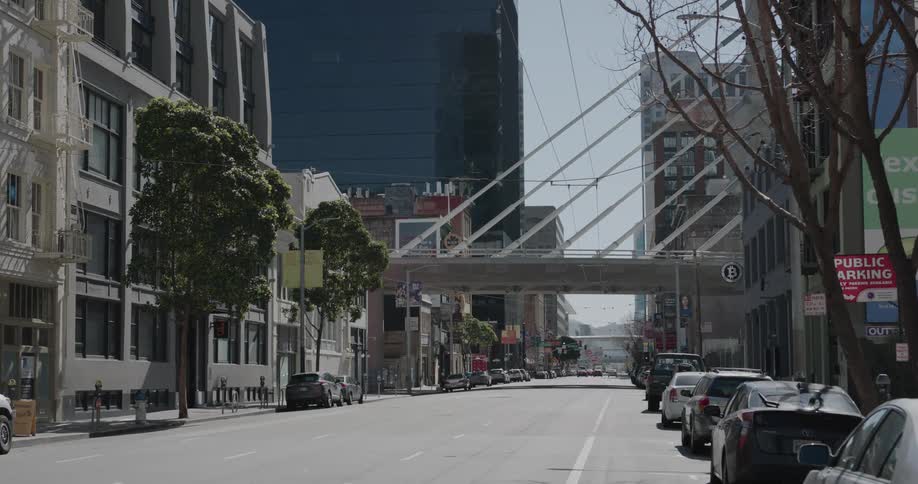A street lined with parked cars in a metropolis during the day
