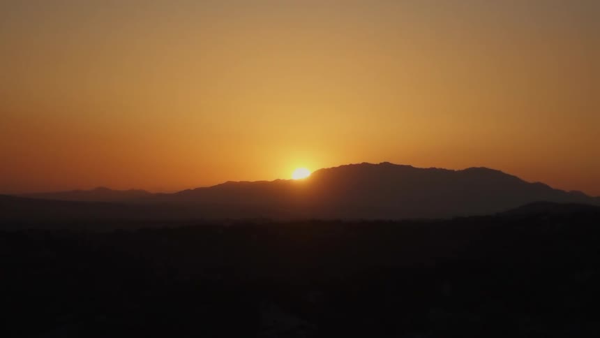 The sun sets behind a hill on the horizon