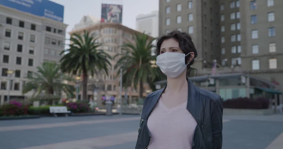 A woman walking in a plaza with a face mask on