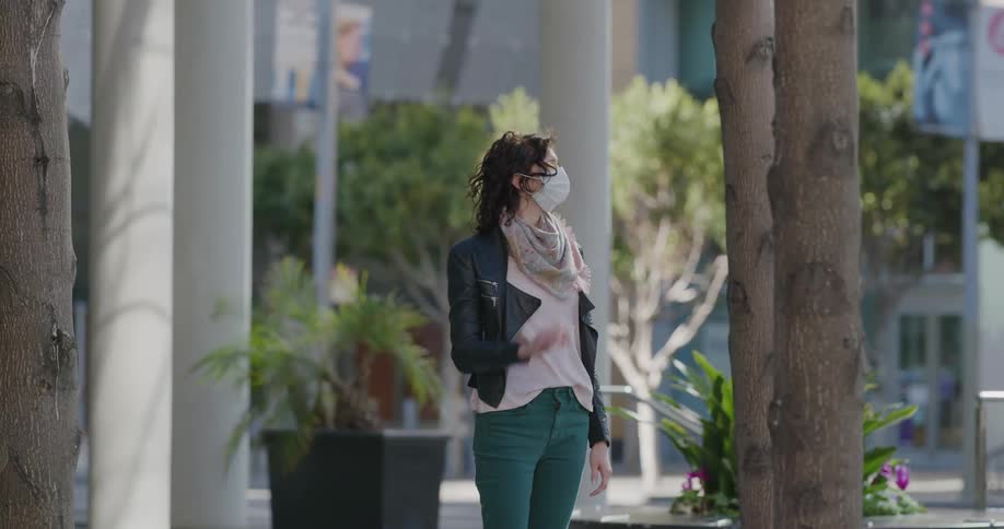 A woman wearing a face mask is standing outside