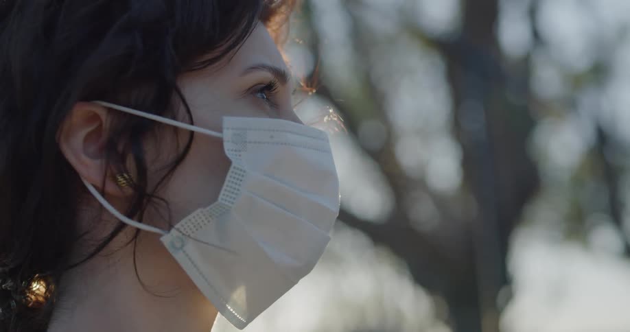 A woman wearing a mask looks around