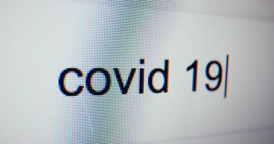 A close up of a monitor typing covid19