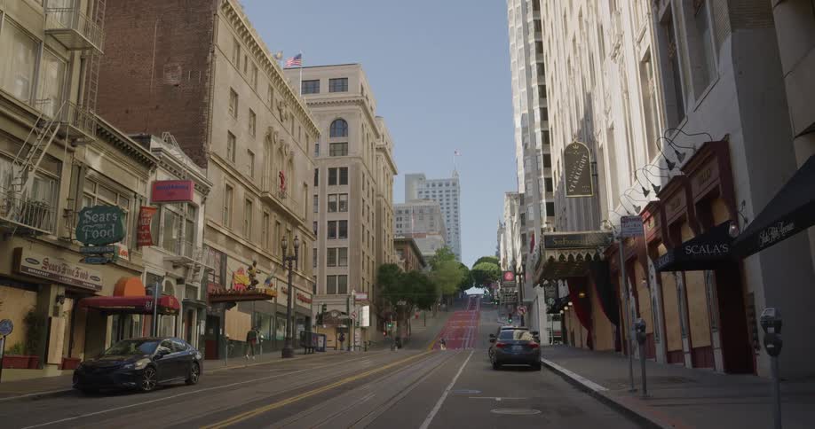 Few pedestrians walk around city street near shops