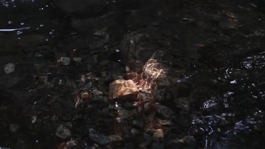 Sun shines on the rock bed of the clear stream