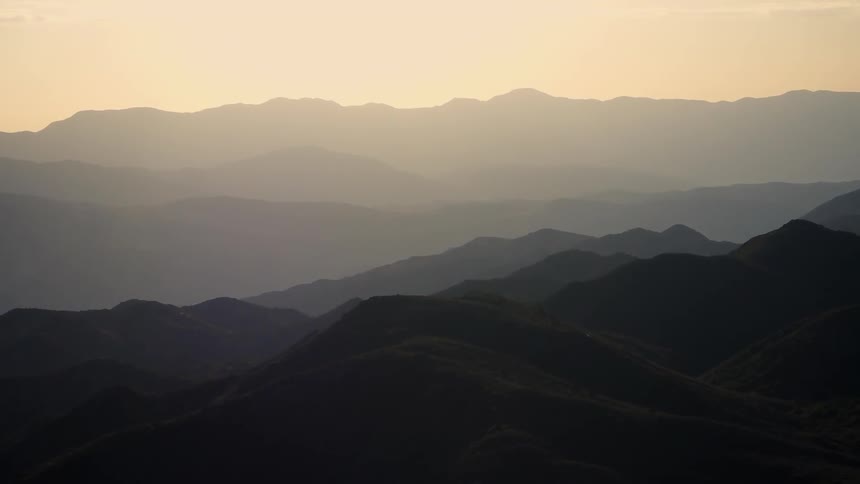 Many mountains with hills during a foggy sunrise