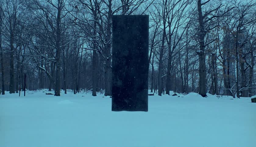 Mystic dark stele stands in the forest at dusk while it snows