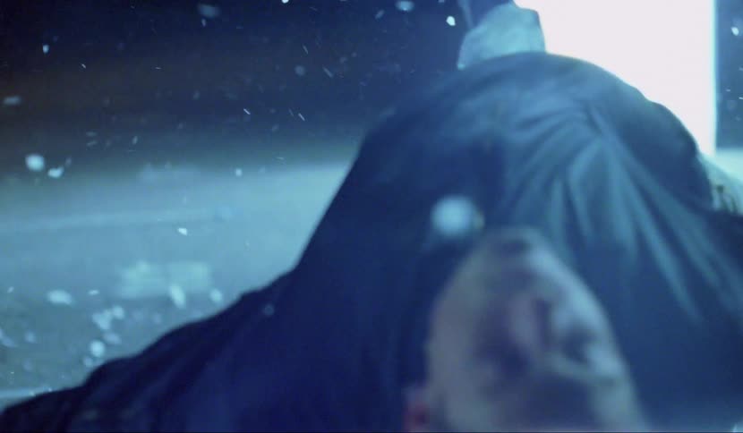 Man floats in parking lot at night with leg extended toward white rectangle of light