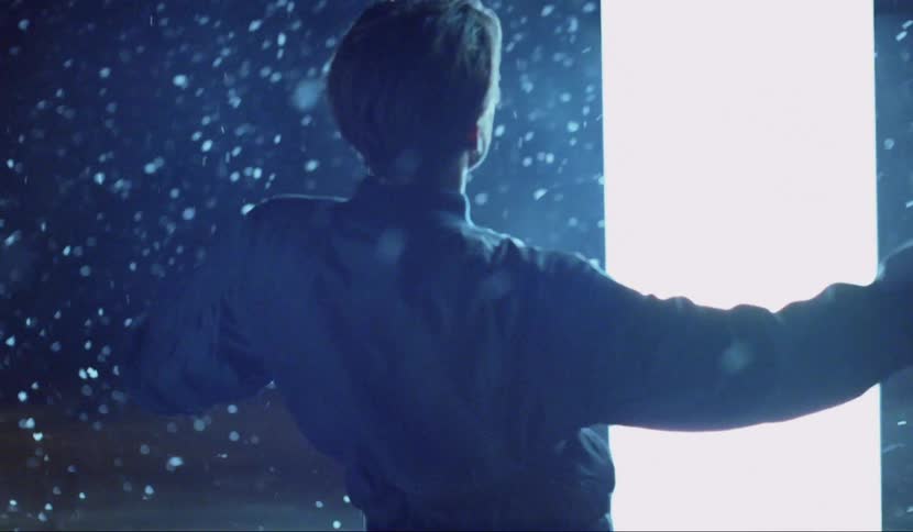 A large panel of white light glows as a man falls backwards and snow seems to rise and float