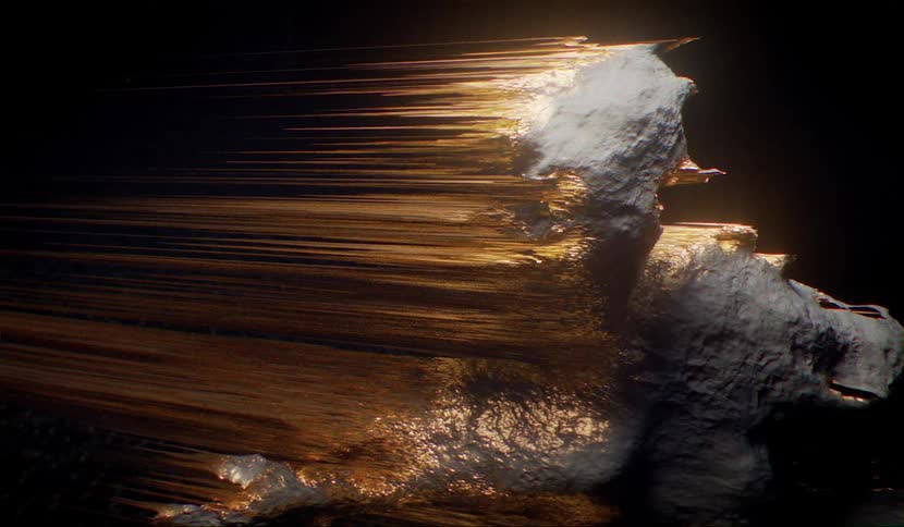 Asteroid like object with gold tendrils streaking out behind rotates against a dark background