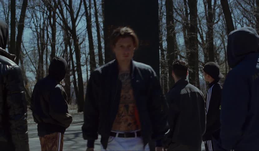 Men stand outdoors on road staring at black obelisk glowing from within