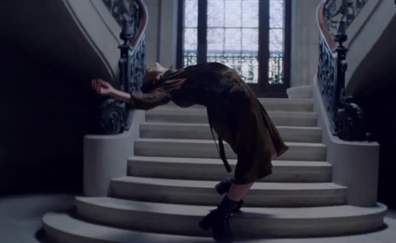 A teenager throws her body backwards on a staircase