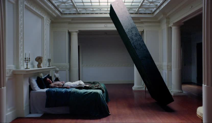 A rendered stone slab balanced precariously over a person