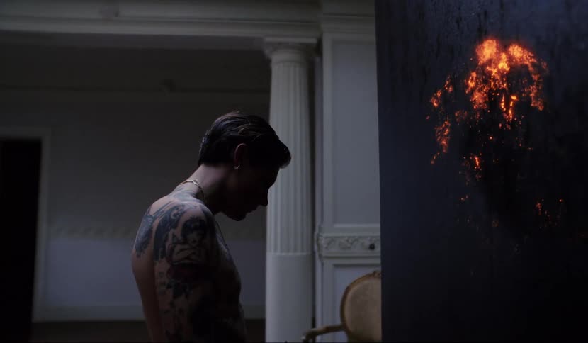 A man standing next to a black pillar that is glowing orange