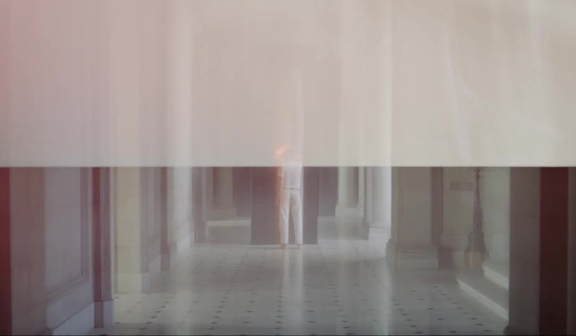 A man stands in a fancy hallway in front of a large black panel which is flashing and glowing orange light