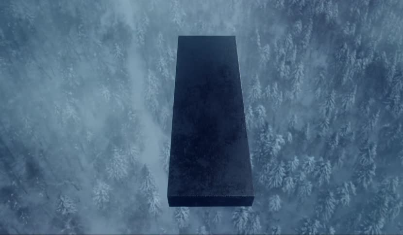 A black pillar descending over a snowy forest