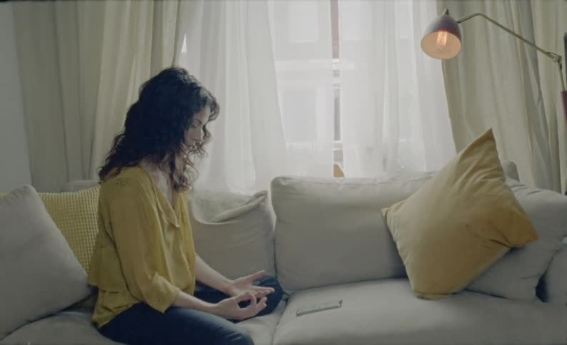 Woman sitting on the sofa uses a smart phone and counts her fingers at home