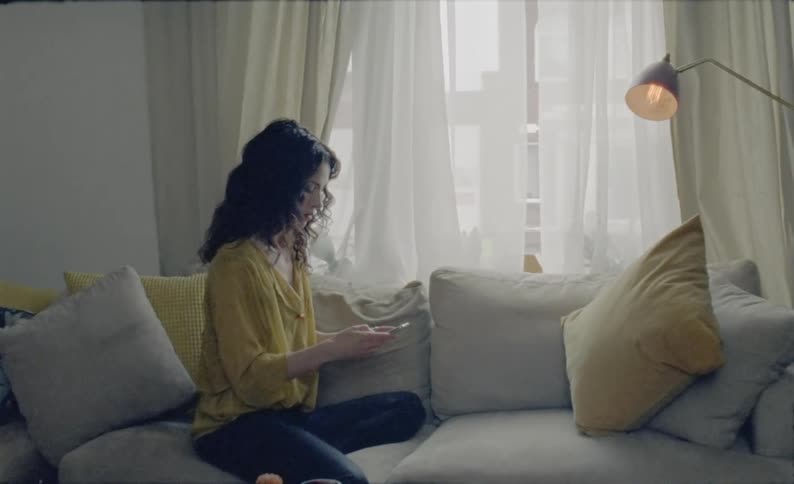 Woman sitting on couch sits up to read text message