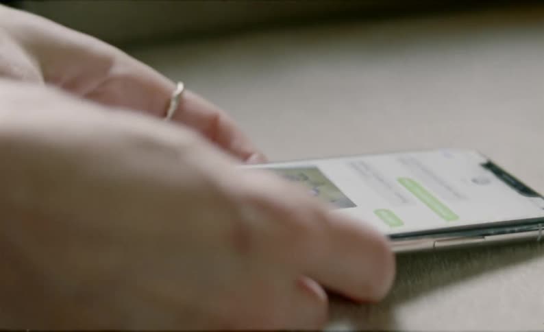 A woman picks up her smart phone to reply to a text message
