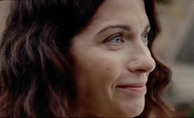 A woman nods her head and fights back tears while listening to someone