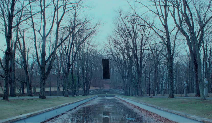 A park with a canal with a black pillar floating over it