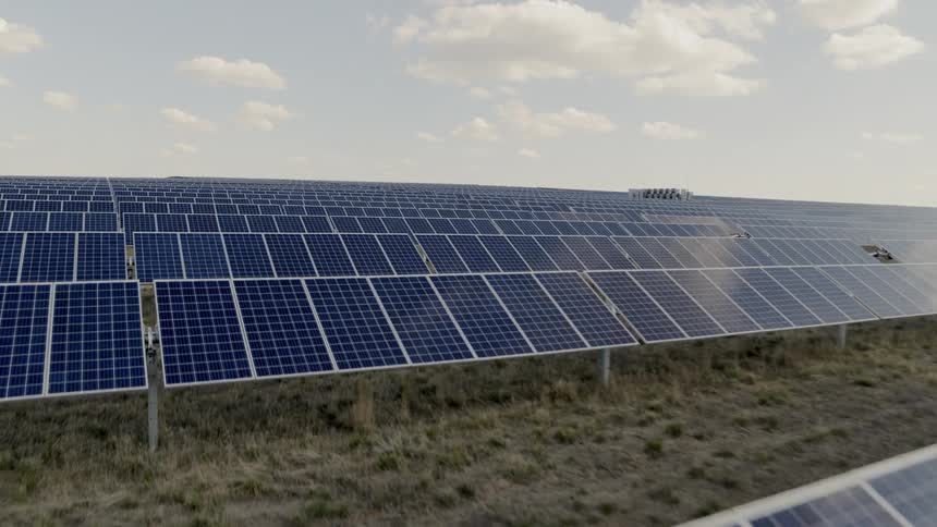 Close up flyover of solar panels temporarily shaded by puffy clouds