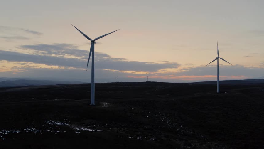 Two wind turbines operating amid a twilight sky