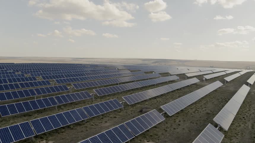 Angled traverse over endless rows of reflective solar panel arrays in the shade