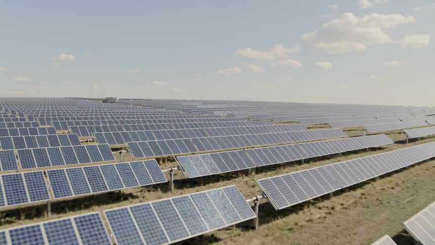 Pullback reveal over row after row of solar panels producing electricity from ample sunshine