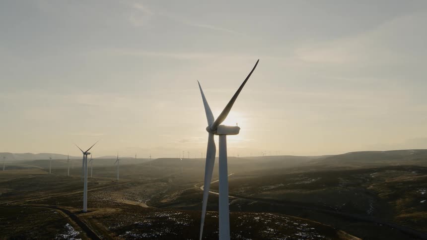 Slow orbit around wind turbines stopped during calm winds as the sun hangs low over the horizon