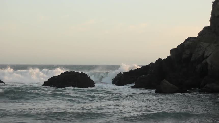 Water is crashing against rocks on a coast