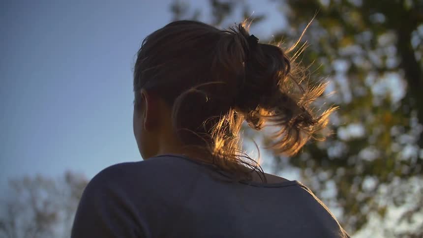 The wind blows a woman's hair on a sunny day