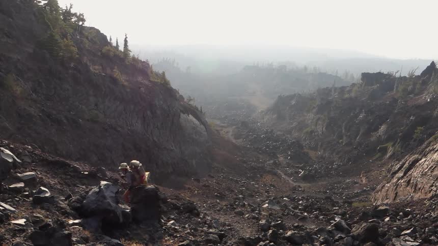 A hiker climbs up a rocky mountain side