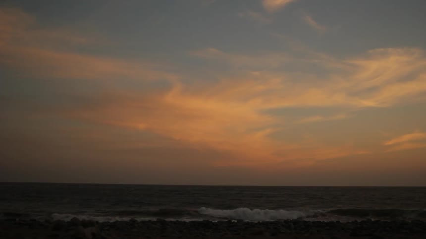 Waves crash on the shore at dusk