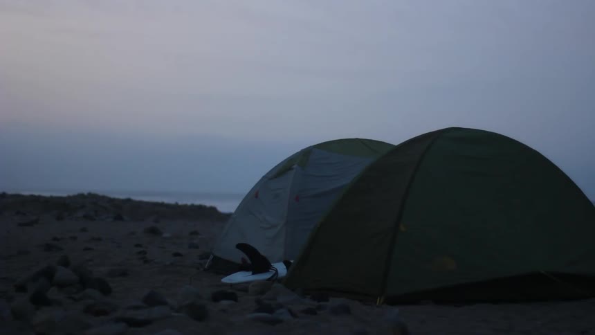 Two tents on a beach at dusk